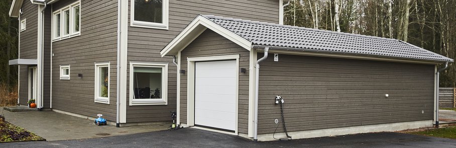 Grått trähus med garage.