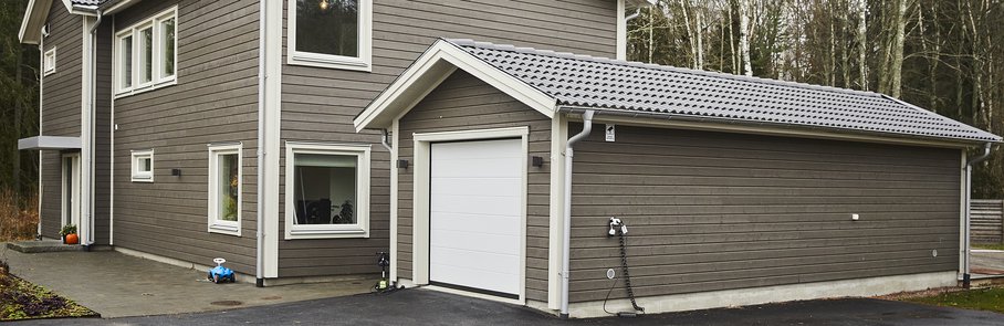 Grått trähus med garage.