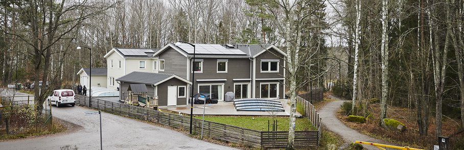 Grått trähus med pool, pooltak och trädäck.