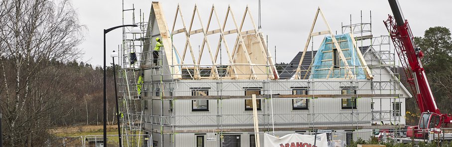 Ett nytt hus i Väsjön under uppbyggnad. En lyftkran arbetar med husets övervåning.