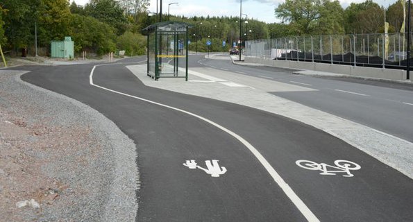 En cykelbana med en busshållplats i bakgrunden.