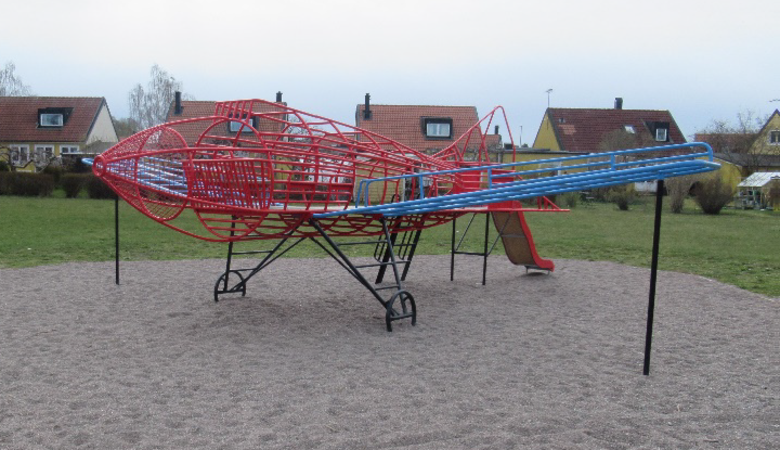 En röd och blå lekställning i en park.