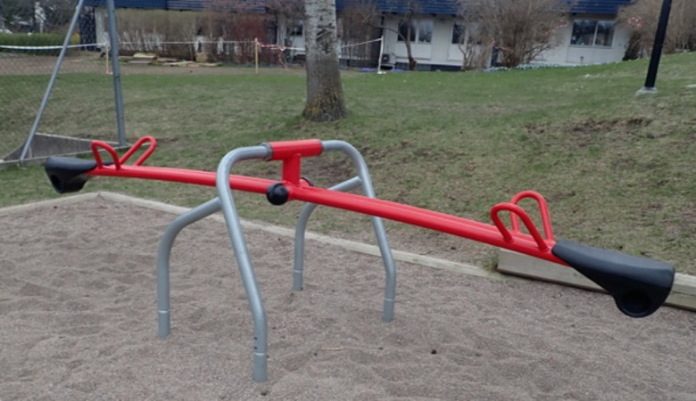 En röd och svart gungbräda i en park.