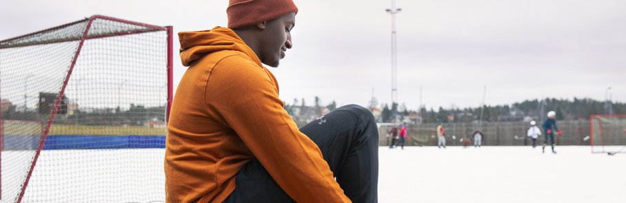 En man sitter på en bänk framför en sjö.