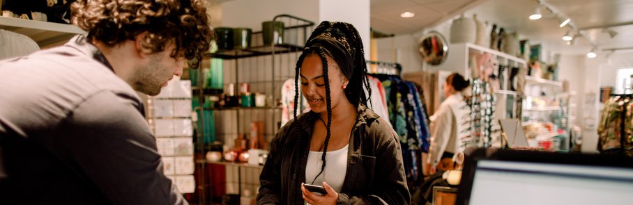 Smiling customer buying clothes from salesman at store