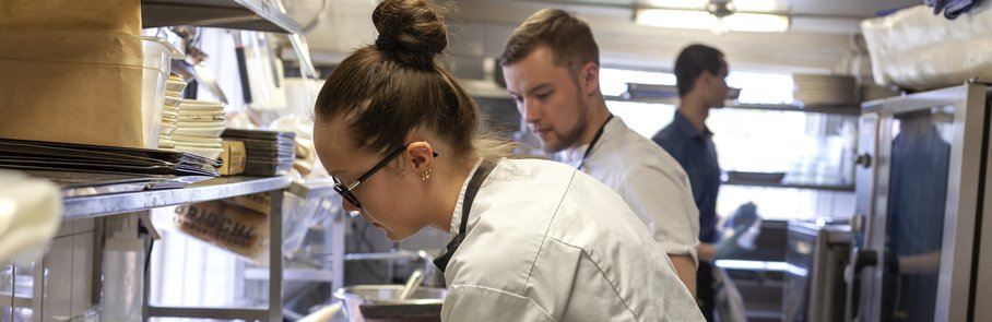 Flera personer i ett restaurangkök förbereder för dagens gäster.