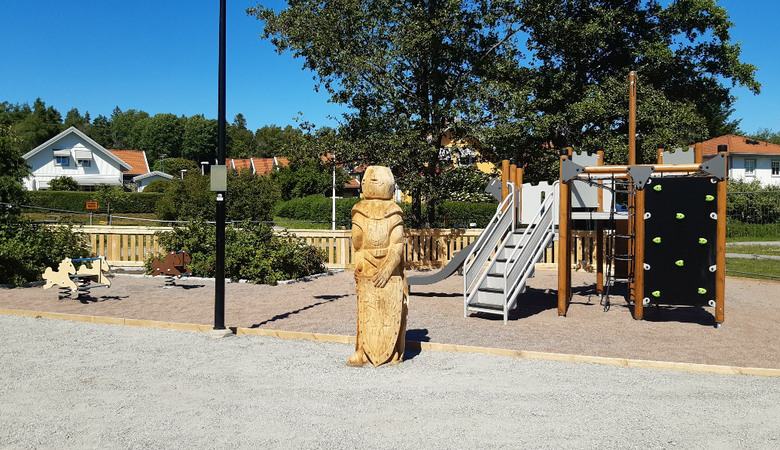 En staty av en person i en park bredvid en lekplats.