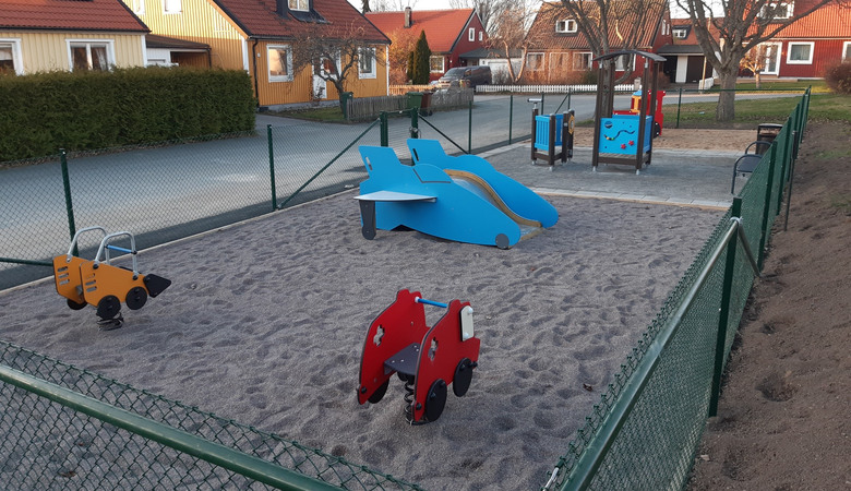 En lekplats i ett bostadsområde med lekutrustning för barn.